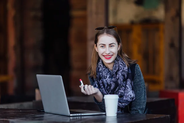 Chica joven sentada detrás de la cafetería en su computadora portátil —  Fotos de Stock