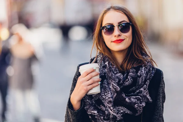 Chica joven caminando por la calle con una taza de café caliente — Foto de Stock