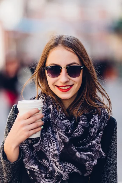 Ung flicka gå på gatan med kopp hett kaffe — Stockfoto