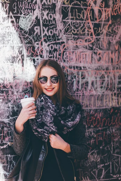 Mooi meisje permanent voor muur met kopje koffie — Stockfoto