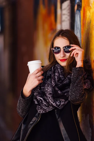 Mooi meisje permanent voor muur met kopje koffie — Stockfoto