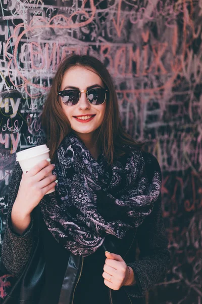 Jolie fille debout devant le mur avec une tasse de café — Photo