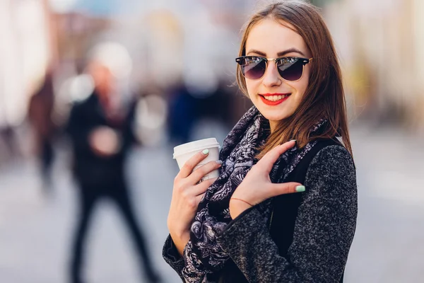 Genç kız sıcak kahve ile sokakta yürürken
