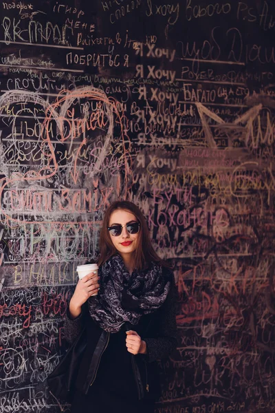 Söt flicka stående framför väggen med fika — Stockfoto