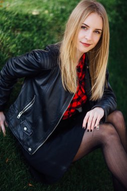 Çimenlerin üzerinde oturan genç güzel kız