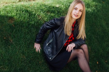 Çimenlerin üzerinde oturan genç güzel kız