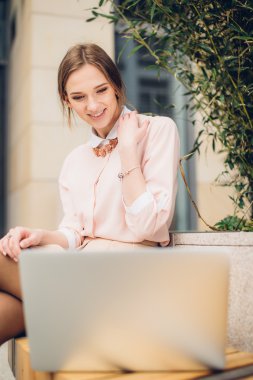 Güzel kadın bankta oturan onu laptop için izliyor