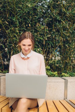 Güzel kadın bankta oturan onu laptop için izliyor