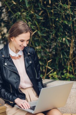 Güzel kadın bankta oturan onu laptop için izliyor