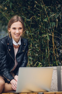 Güzel kadın bankta oturan onu laptop için izliyor