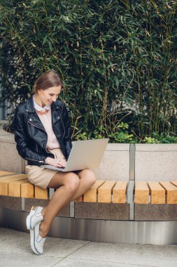 Güzel kadın bankta oturan onu laptop için izliyor