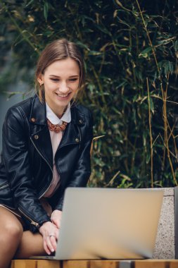 Güzel kadın bankta oturan onu laptop için izliyor