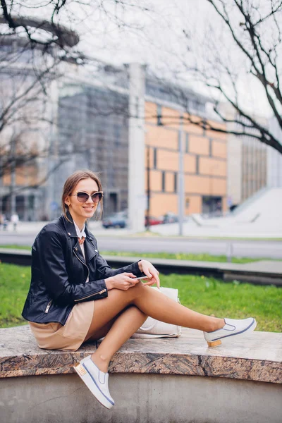 Vacker kvinna sitter på bänken, talar hennes telefon — Stockfoto