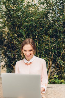 Güzel kadın bankta oturan onu laptop için izliyor