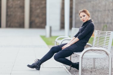 Buindings önünde bankta oturan genç kadın