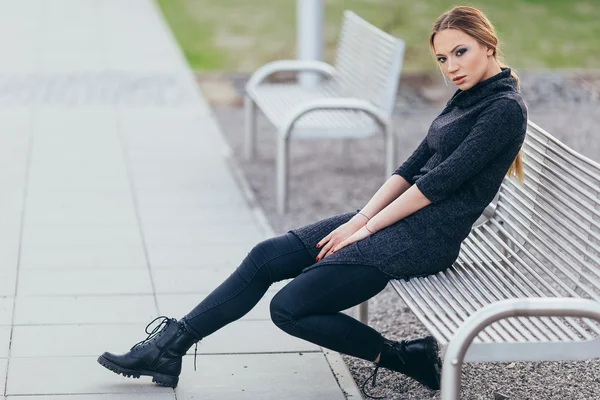 Buindings önünde bankta oturan genç kadın — Stok fotoğraf