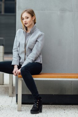 Buindings önünde bankta oturan genç kadın