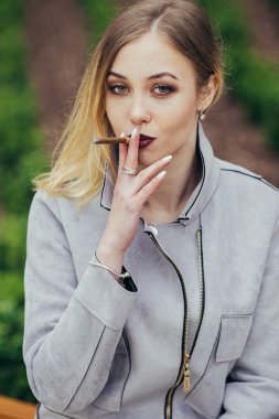 Genç kadın duman sigara bankta