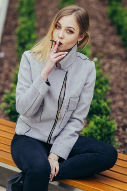 Genç kadın duman sigara bankta