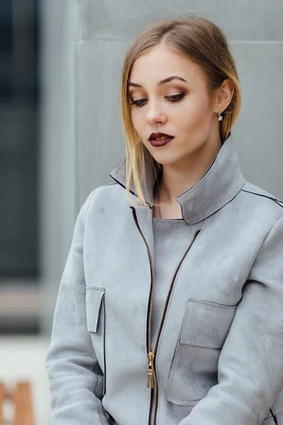 Young woman sitting on the bench in front of buindings — Stock Photo, Image