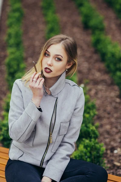 Ung kvinna röka cigarett på bänken — Stockfoto