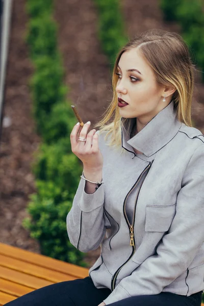 Giovane donna fumare sigaretta sulla panchina — Foto Stock