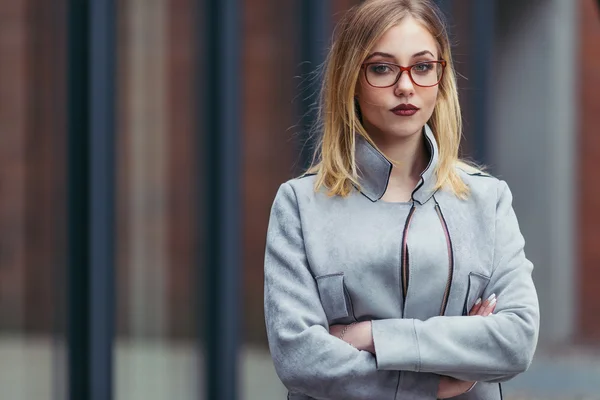 Jonge vrouw staande voor kantoorgebouwen — Stockfoto