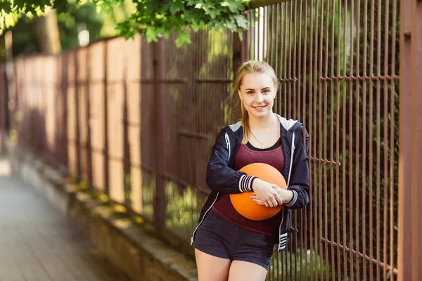 Σπορ κορίτσι στέκεται με μπάλα μπάσκετ — Φωτογραφία Αρχείου