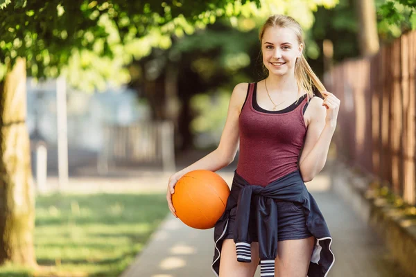 Sportovní dívka stojící s basketbalový míč — Stock fotografie