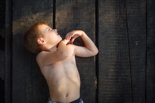 Prachtige kleine jongen liggend op de grond en glimlach — Stockfoto