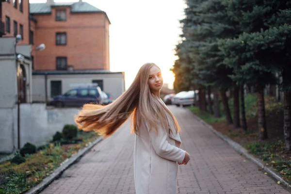 Chica con el pelo muy largo de pie sobre el fondo de la puesta del sol — Foto de Stock