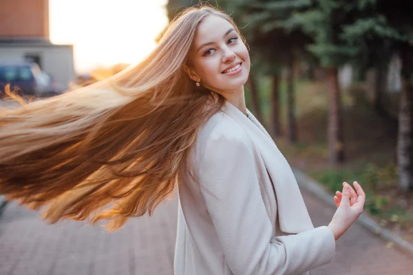 Menina com cabelos muito longos em pé no fundo do pôr do sol — Fotografia de Stock