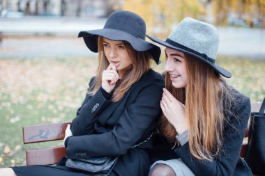 Bankta oturan ve kamera için poz iki genç kız