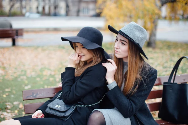 Due giovani ragazze sedute sulla panchina e in posa per la fotocamera — Foto Stock