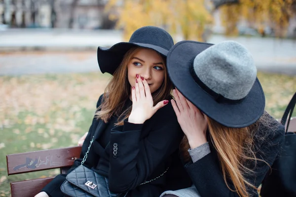 Due giovani ragazze sedute sulla panchina e in posa per la fotocamera — Foto Stock