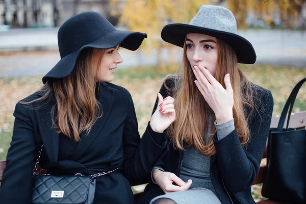 Duas meninas sentadas no banco e posando para a câmera — Fotografia de Stock