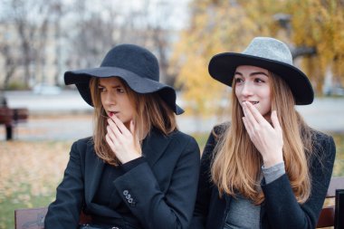 Bankta oturan ve kamera için poz iki genç kız