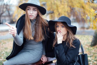 Bankta oturan ve kamera için poz iki genç kız