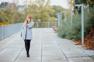 Sokakta yürüyen ve telefon üzerinde sarı saçlı kadın