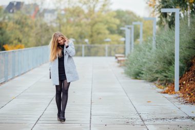Sokakta yürüyen ve telefon üzerinde sarı saçlı kadın
