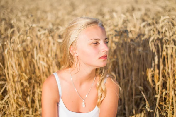 Chica joven está sonriendo en el campo, puesta de sol, hora de verano — Foto de Stock