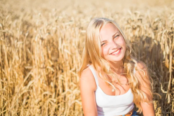 Chica joven está sonriendo en el campo, puesta de sol, hora de verano — Foto de Stock
