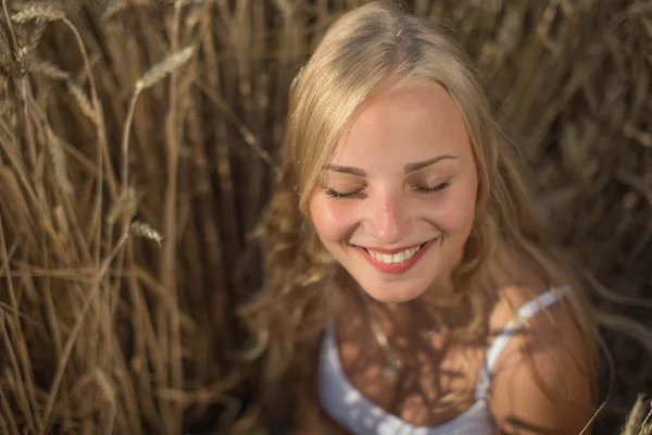 Chica joven está sonriendo en el campo, puesta de sol, hora de verano — Foto de Stock