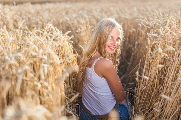 Chica joven está sonriendo en el campo, puesta de sol, hora de verano — Foto de Stock