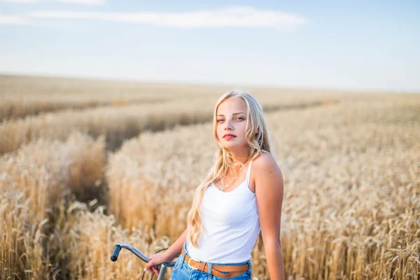 Chica joven está sonriendo en el campo, puesta de sol, hora de verano —  Fotos de Stock