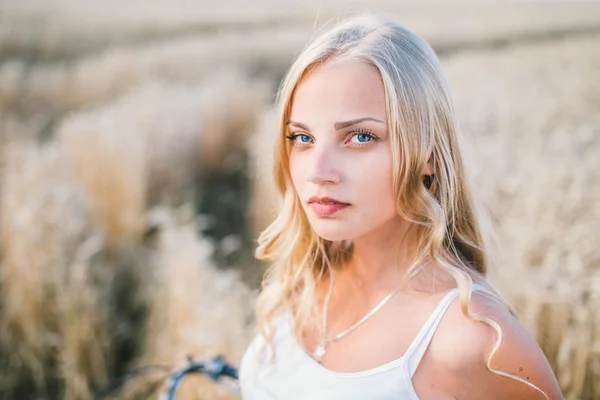 Chica joven está sonriendo en el campo, puesta de sol, hora de verano — Foto de Stock