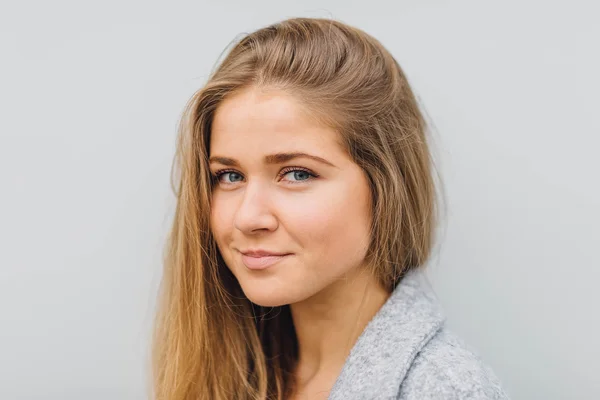 Blonde young woman standing behind the wall and posing ti camera