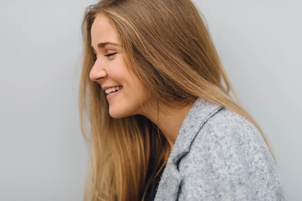 Blonde young woman standing behind the wall and posing ti camera