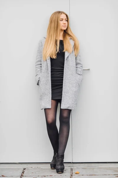 Blonde junge Frau steht hinter der Wand und posiert vor der Kamera — Stockfoto