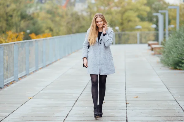 Frau mit blonden Haaren geht auf die Straße und telefoniert — Stockfoto